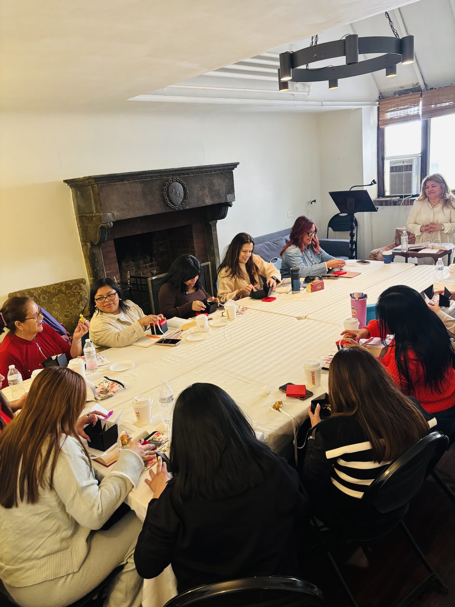 Women gathered around a table in prayer at a Crowned in Grace retreat